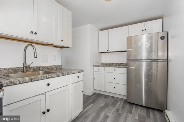 a kitchen with cabinets appliances wooden floor and a window
