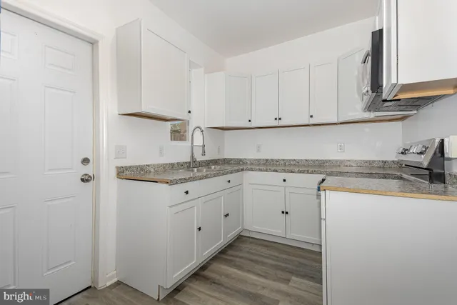 a kitchen with granite countertop white cabinets and white appliances