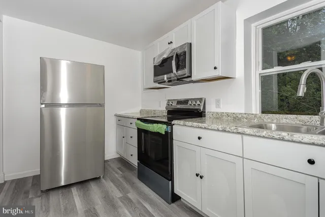 a kitchen with stainless steel appliances granite countertop a refrigerator a microwave a sink and cabinets