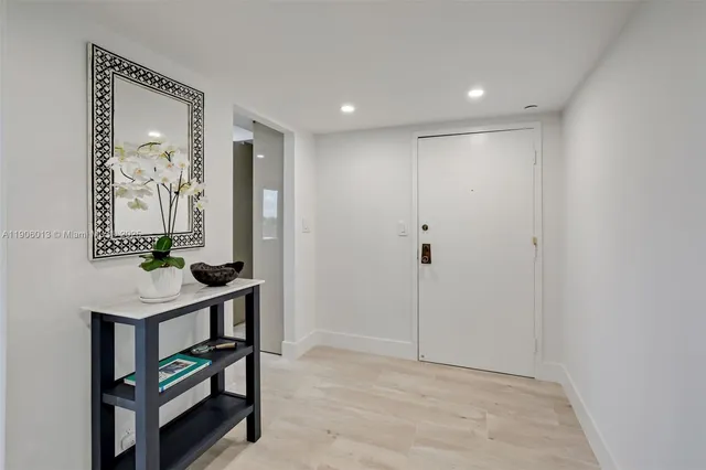 a view of a hallway with front door and wooden floor