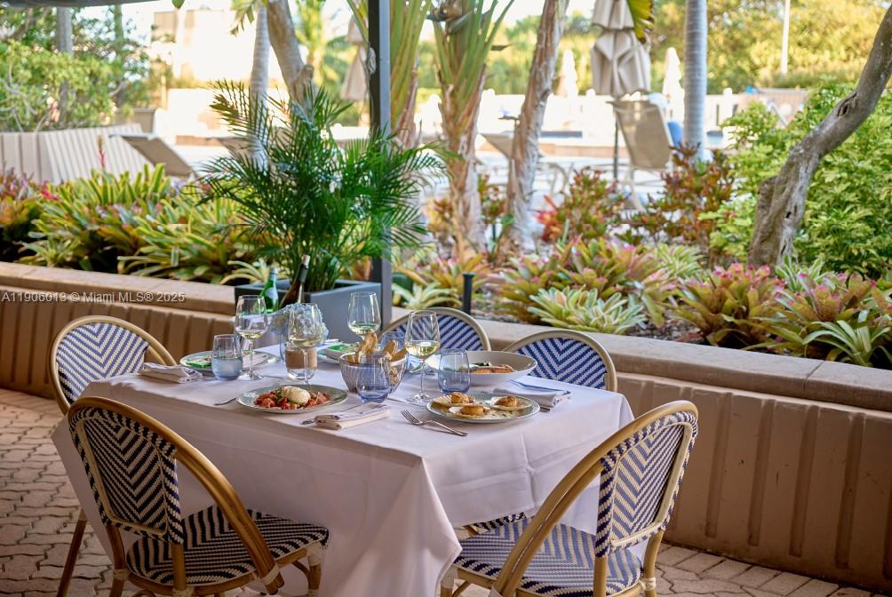 1111 Crandon Boulevard, Unit A507 Key Biscayne, FL 33149 - Photo 23 of 23 a table and chairs with potted plants and wooden fence