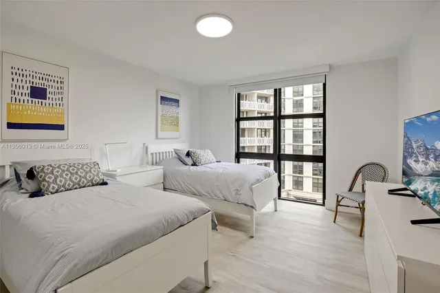 a bedroom with two beds and a large mirror next to a window