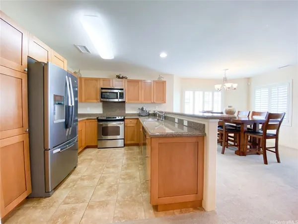 a kitchen with stainless steel appliances granite countertop a refrigerator a stove a sink a dining table and chairs