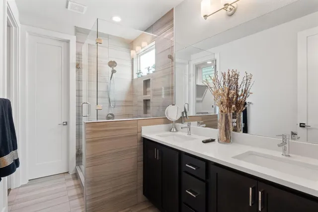 a bathroom with a double vanity sink mirror and shower