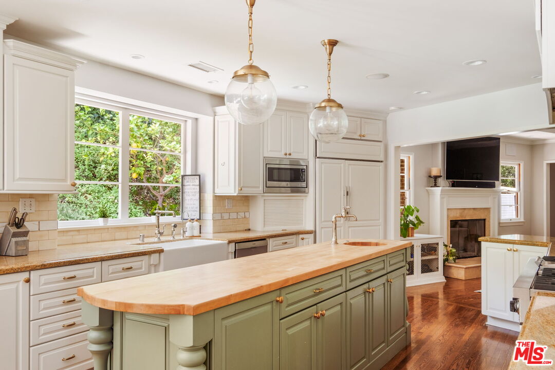1265 Inverness Drive Pasadena, CA 91103 - Photo 24 of 56 a kitchen with a sink a center island a wooden floor and a large window