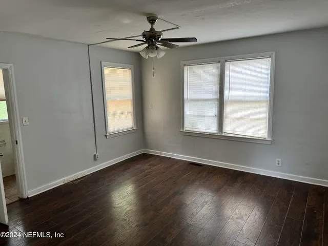 a view of an empty room with wooden floor and a window