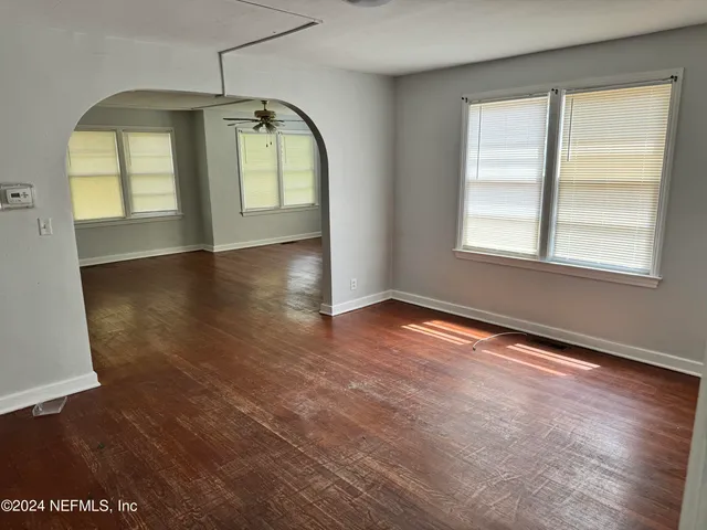 an empty room with wooden floor and windows