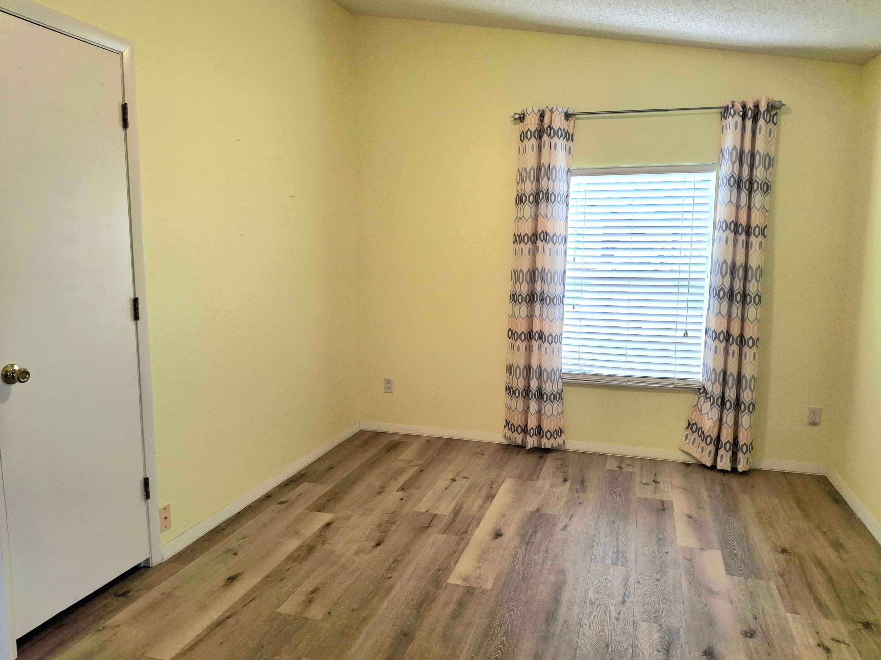 8483 Schefflera Court Port St. Lucie, FL 34952 - Photo 22 of 33 an empty room with wooden floor and a window