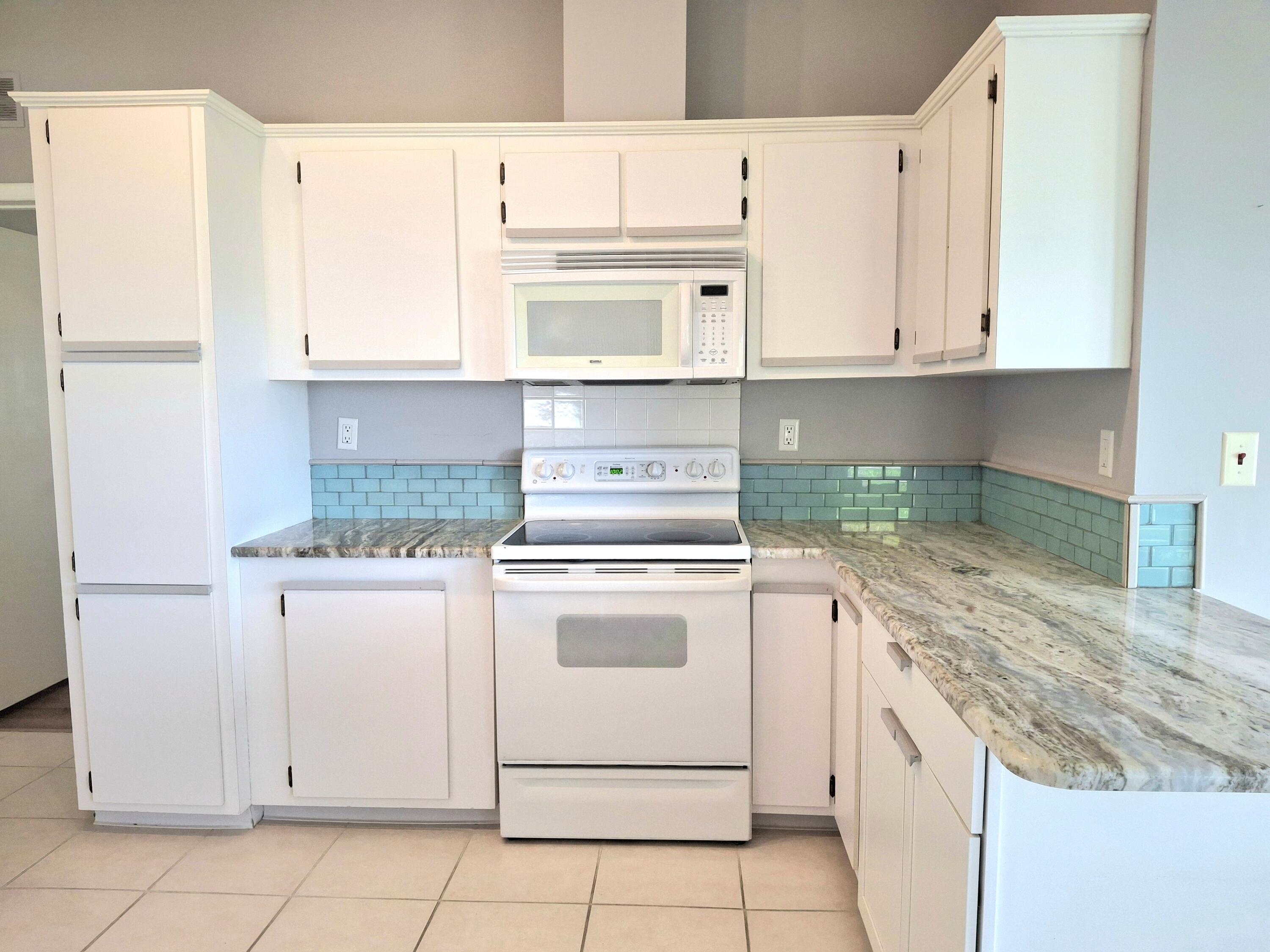 8483 Schefflera Court Port St. Lucie, FL 34952 - Photo 6 of 33 a kitchen with granite countertop white cabinets and white appliances