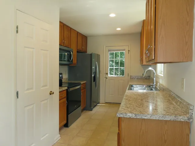 a kitchen with granite countertop a refrigerator stove and sink
