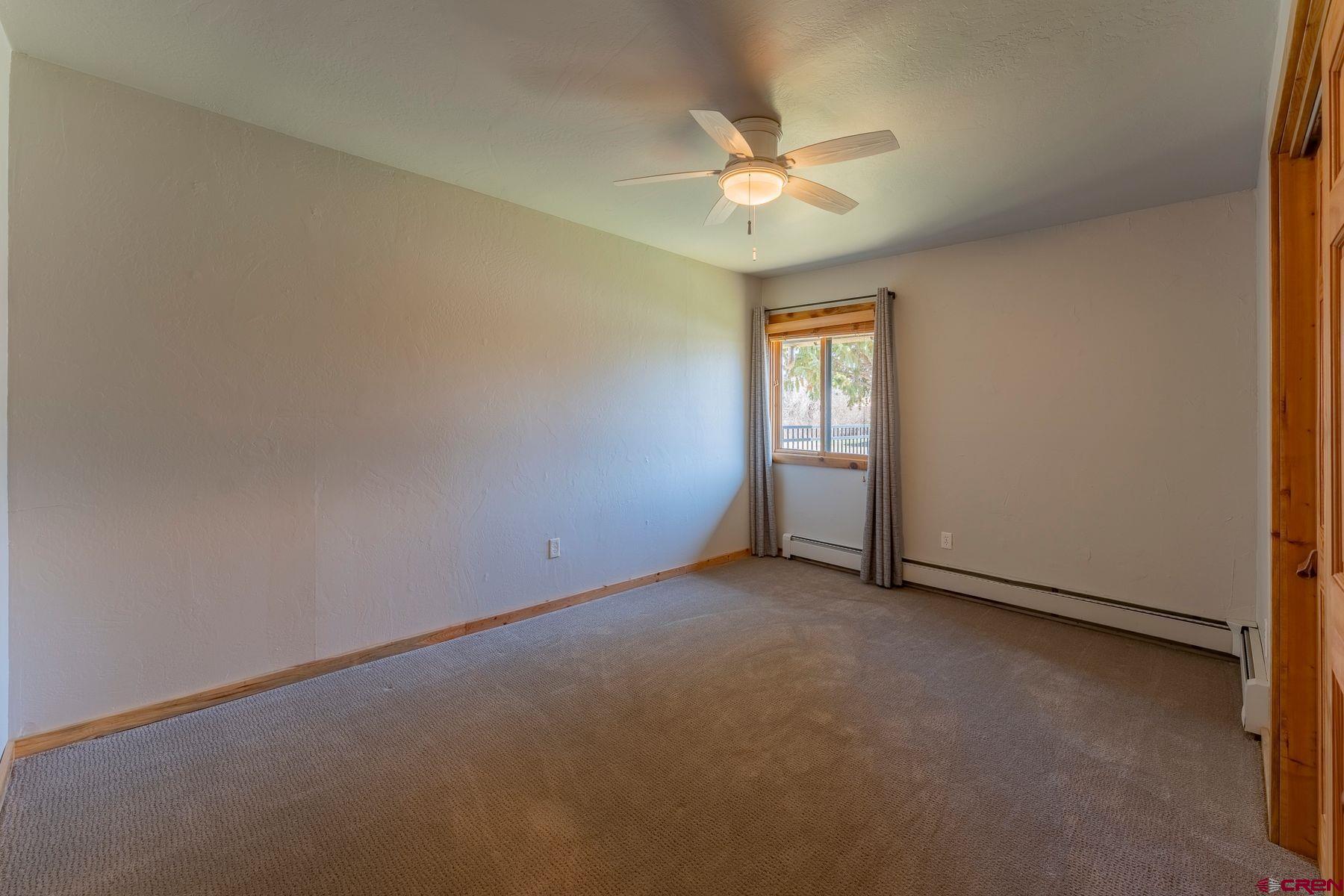 169 Camino Del Rio, Unit 8 Gunnison, CO 81230 - Photo 19 of 35 an empty room with a chandelier fan and windows