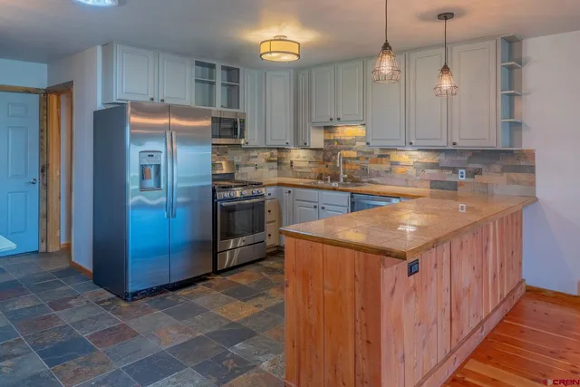 a kitchen with stainless steel appliances granite countertop a sink and a refrigerator