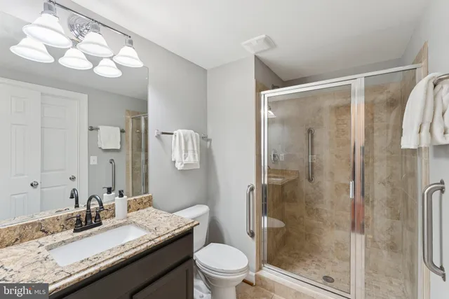 a bathroom with a granite countertop sink toilet a mirror and shower