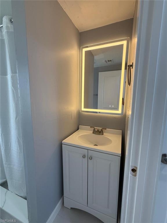 5317 Fleming Street Naples, FL 34113 - Photo 7 of 8 White vanity with integrated sink, brushed nickel faucet, and illuminated mirror