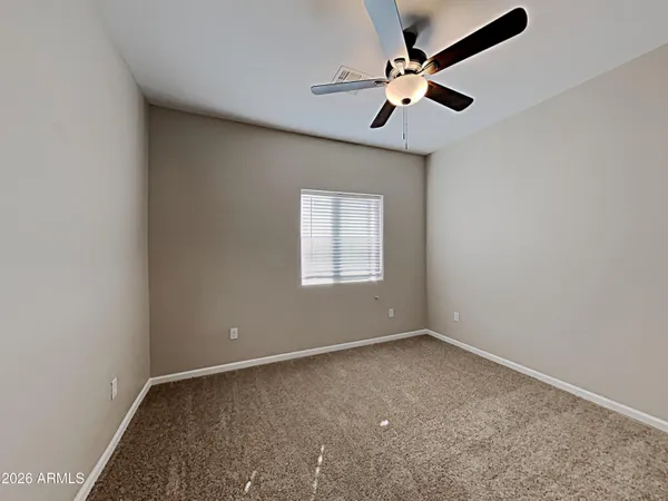 an empty room with a window and a ceiling fan