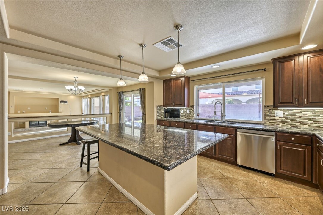 6239 Mustang Spring Avenue Las Vegas, NV 89139 - Photo 16 of 28 Kitchen with a raised ceiling, decorative light fixtures, a dishwasher, and dark granite countertops
