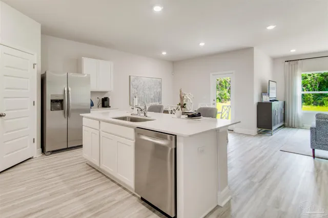a kitchen with stainless steel appliances a sink a stove a table and chairs