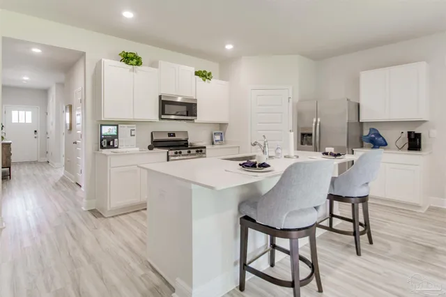 a kitchen with a sink a stove and white cabinets with wooden floor