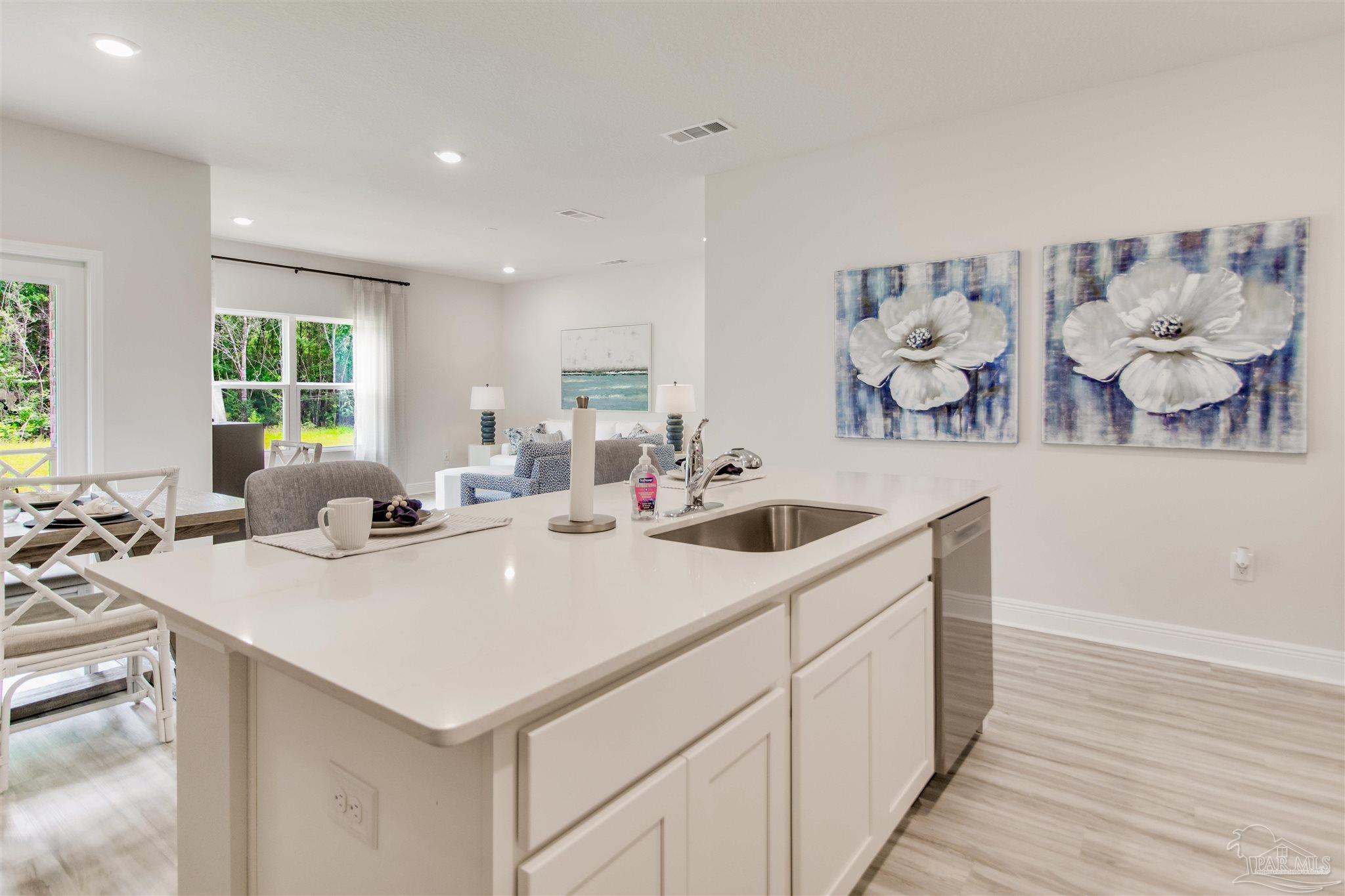 4745 Redhead Court Pace, FL 32571 - Photo 17 of 44 a kitchen with a sink a stove and white cabinets with wooden floor