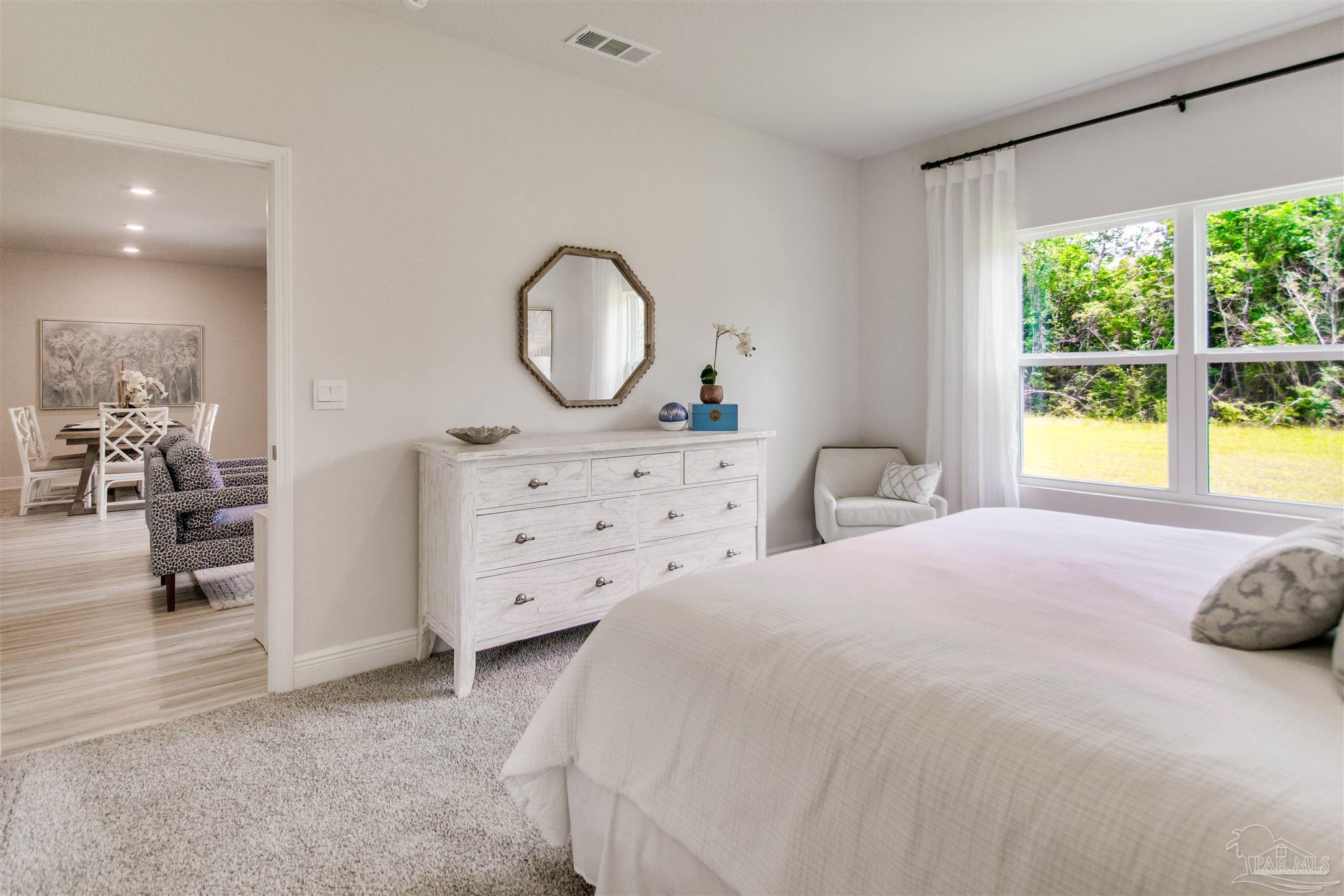 4745 Redhead Court Pace, FL 32571 - Photo 25 of 44 a spacious bedroom with a bed a dresser and windows