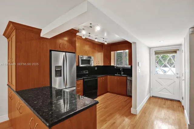 a kitchen with stainless steel appliances granite countertop a refrigerator a sink and a stove