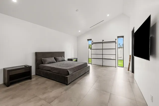 a spacious bedroom with a bed and a flat screen tv