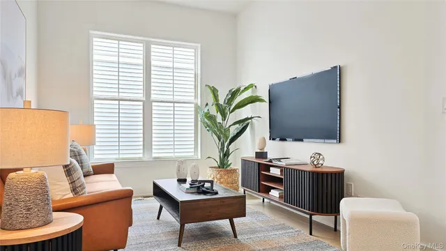 a living room with furniture a flat screen tv and a window