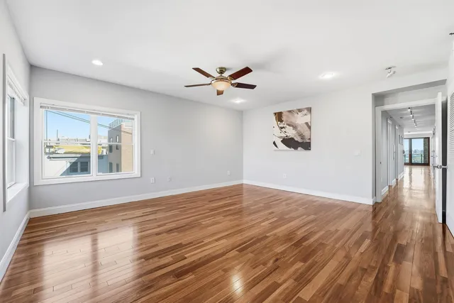 a view of an empty room with window and wooden floor