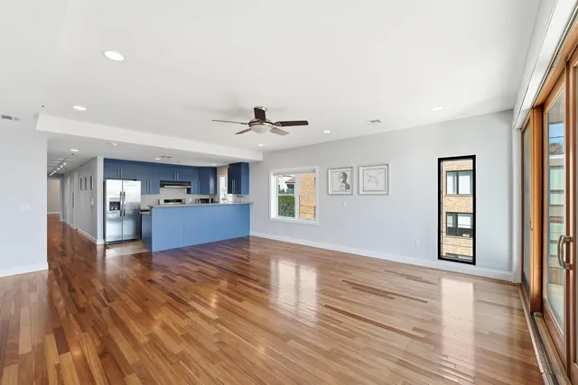 a view of empty room with wooden floor and kitchen view