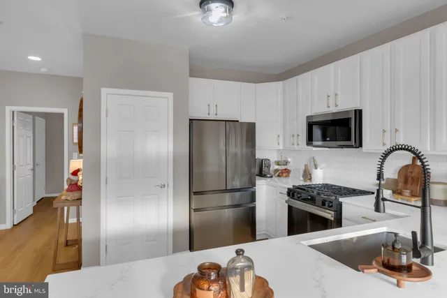 a kitchen with stainless steel appliances granite countertop a refrigerator a stove and a sink with wooden floor