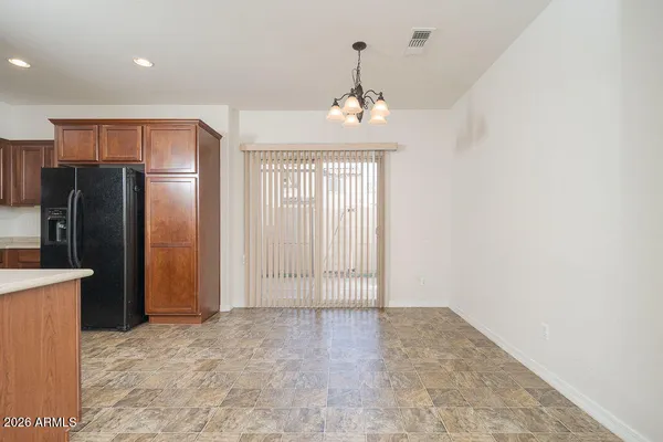 an empty room with a chandelier fan and refrigerator
