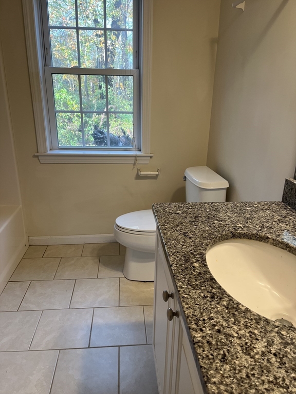 154 Prospect Street, Unit 154 Acton, MA 01720 - Photo 7 of 10 a bathroom with a granite countertop sink a toilet a window and a shower