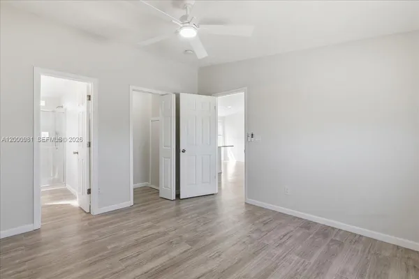 an empty room with wooden floor and a ceiling fan