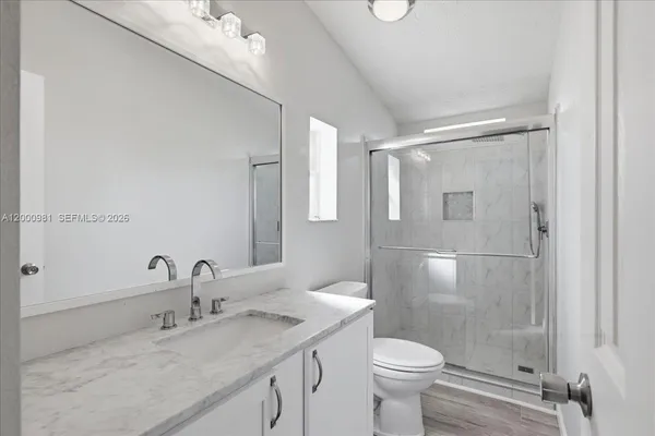 a bathroom with a granite countertop sink toilet and shower
