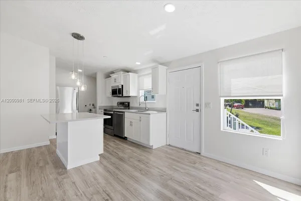 a kitchen with white cabinets and window