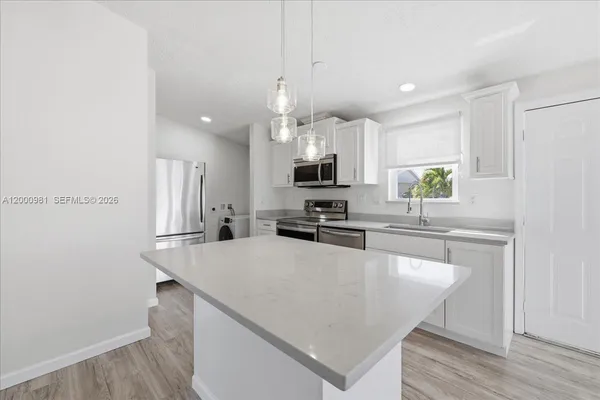 a kitchen with kitchen island a white counter top space a sink and appliances