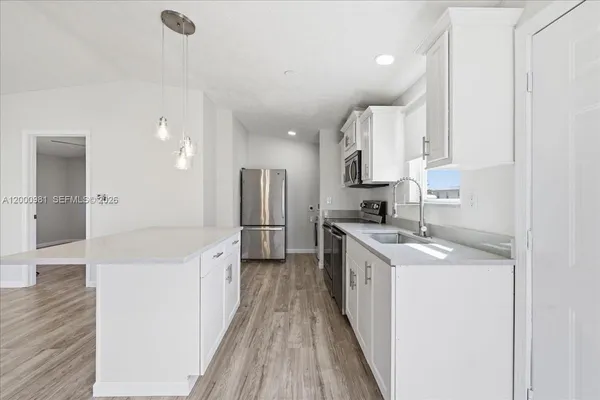 a kitchen with white cabinets appliances and sink