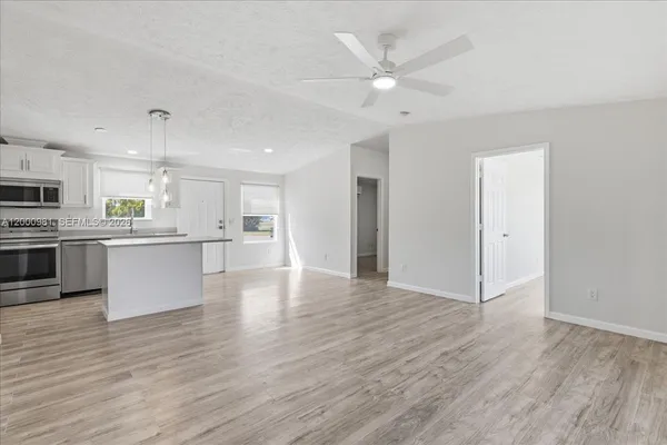 a view of kitchen with granite countertop stainless steel appliances cabinets a sink and a wooden floor