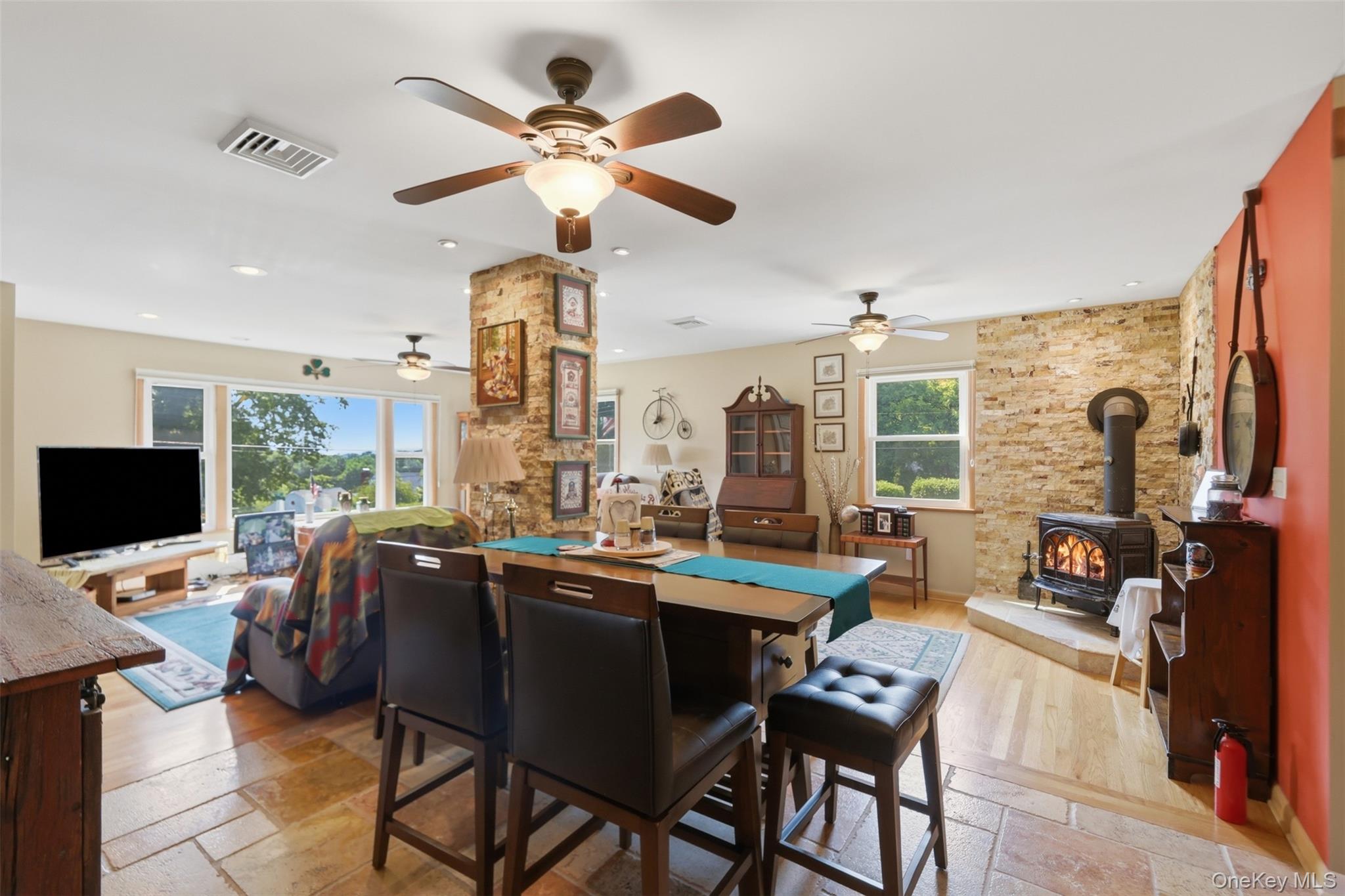 1 Hiko Place Fishkill, NY 12524 - Photo 13 of 41 Open concept living space featuring stone-finish flooring, a stone-clad structural column, and a prominent wood-burning stove with a stone hearth