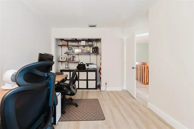a view of a hallway with wooden floor and a bathroom
