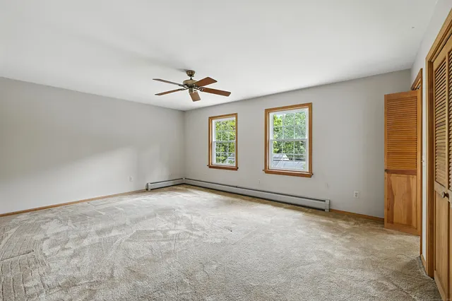 a view of empty room with wooden floor and fan