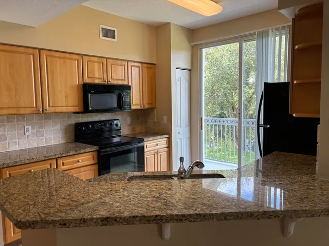 a kitchen with kitchen island granite countertop a sink stove top oven and microwave