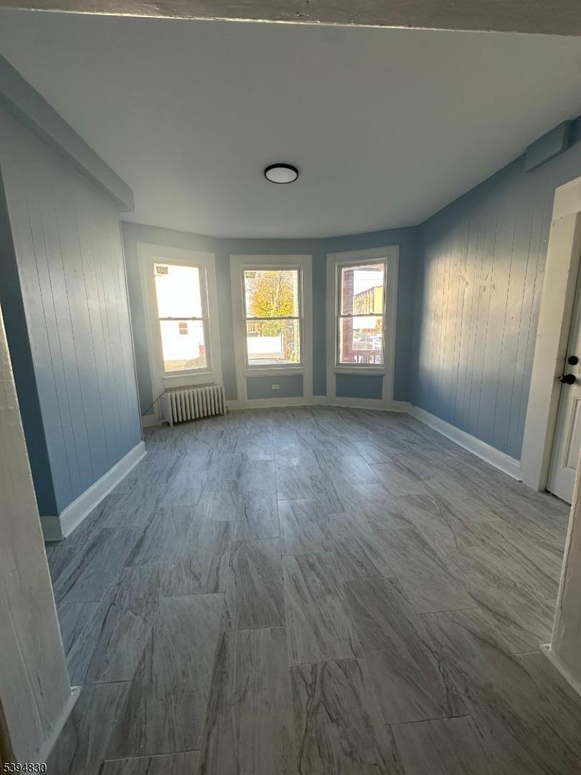 334 11th Avenue, Unit 2 Paterson, NJ 07514 - Photo 2 of 5 an empty room with wooden floor and windows