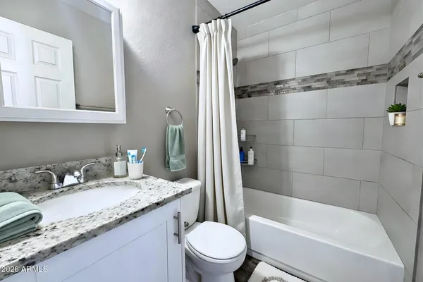 a bathroom with a granite countertop sink toilet and shower