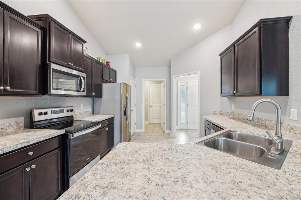 5134 Jenson Avenue Spring Hill, FL 34608 - Photo 14 of 49 a kitchen with stainless steel appliances granite countertop a sink stove and refrigerator