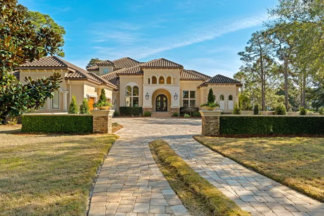 a view of a white house with a big yard plants and large trees