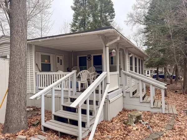 a view of a white house with large windows and a small yard and wooden fence