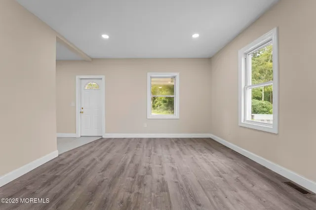 an empty room with wooden floor and windows