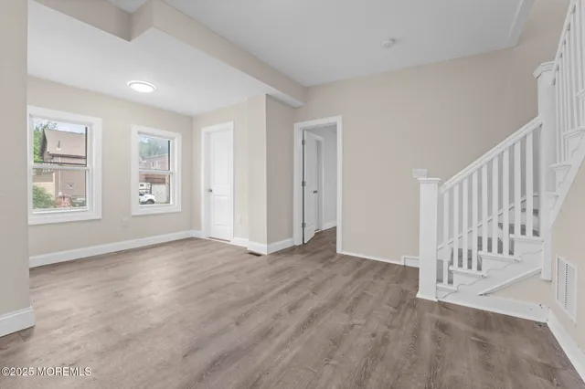 a view of an empty room with window and wooden floor