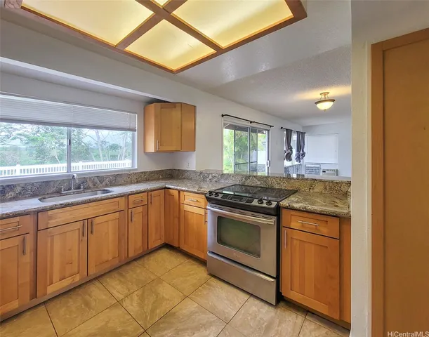 a kitchen with stainless steel appliances granite countertop a stove a sink and a microwave